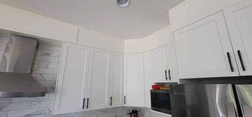 A finished white shaker kitchen with a stainless range hood