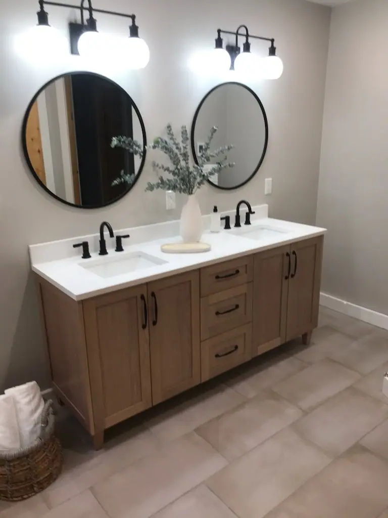 A finished double vanity with round black mirrors