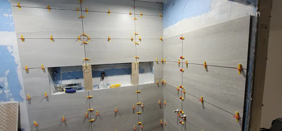 Large-format tile going up on a levelling system, niche framed in